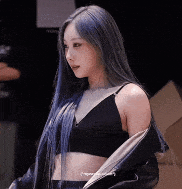 a woman with blue hair is wearing a black crop top and a black jacket