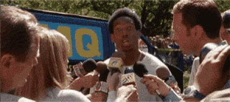 a man is being interviewed by a group of reporters with a sign in the background that says ' 10 '