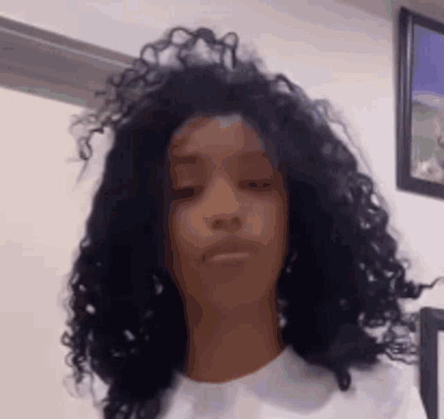 a woman with curly hair is wearing a white t-shirt .