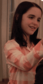 a young girl wearing a pink and white plaid shirt smiles