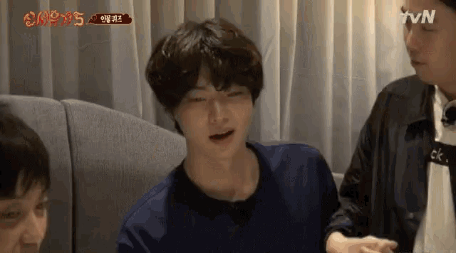 a man is crying while sitting on a couch next to a man .