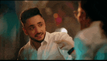 a man in a white shirt is pointing at another man 's face