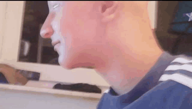 a close up of a man 's face and neck while sitting in front of a window .