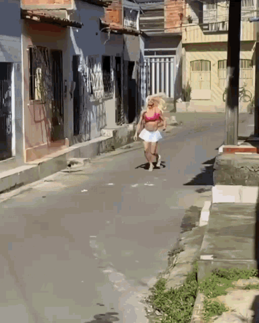 a woman in a pink top and white skirt is walking down the street