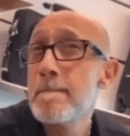 a man with glasses and a beard is making a face .