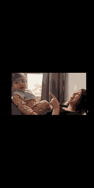 a woman is sitting on a couch holding a baby in her lap .