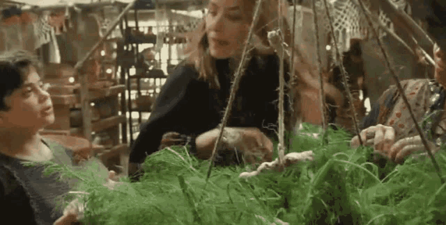 a group of people are sitting around a table playing with a plant .