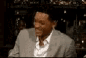 a man in a suit and white shirt is smiling in a blurry photo .