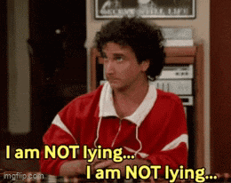 a man in a red jacket is sitting at a table and says i am not lying