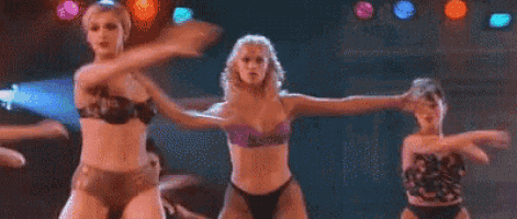 a group of three women in bikinis are dancing on a stage .