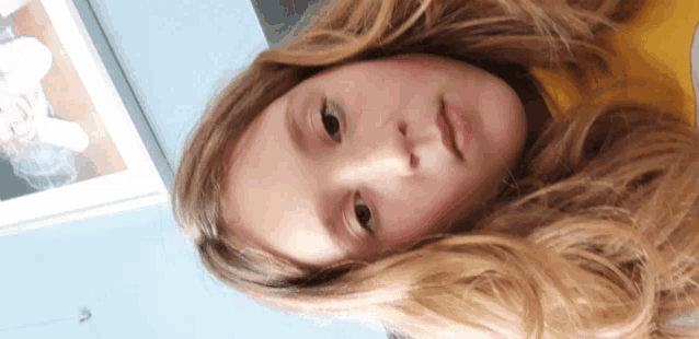 a young girl with long blonde hair is looking down at the camera