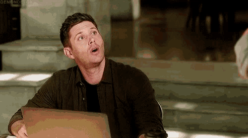 a man is sitting at a table with a laptop and making a funny face .