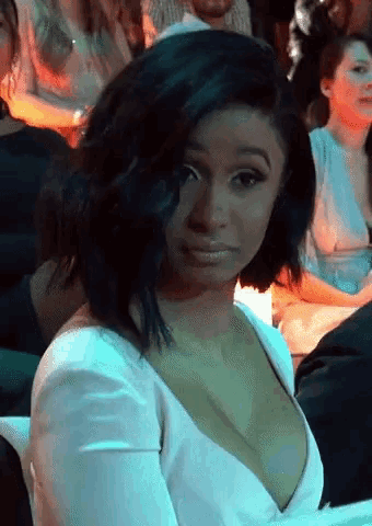 a woman in a white dress with a plunging neckline is sitting in a crowd