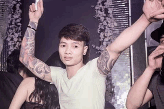 a man with a tattoo on his arm is standing in a crowd of people at a party .