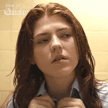 a woman with red hair looks at herself in a mirror with the words son of a glitch above her