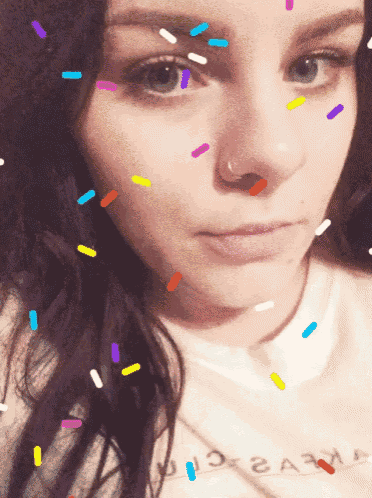 a close up of a woman 's face with sprinkles on it and a white shirt that says ' a '