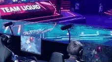 a man is sitting in front of a computer in a stadium watching a video game .