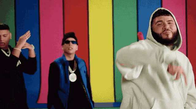 three men are dancing in front of a colorful wall