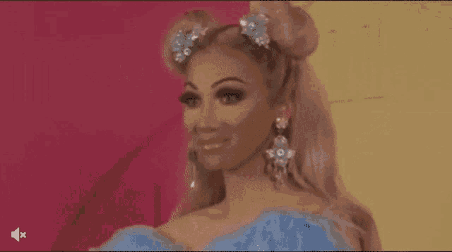 a woman with pink hair and a blue dress is standing in front of a pink wall .