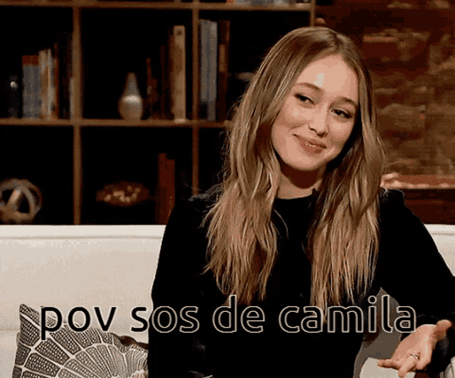 a woman sitting on a couch with the words pov sos de camila written below her