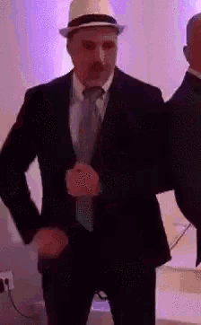 a man in a suit and hat is dancing with another man in a suit and tie .