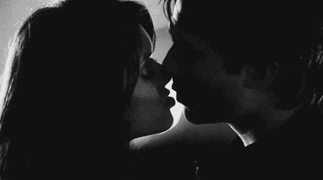 a man and a woman are kissing in a black and white photo .
