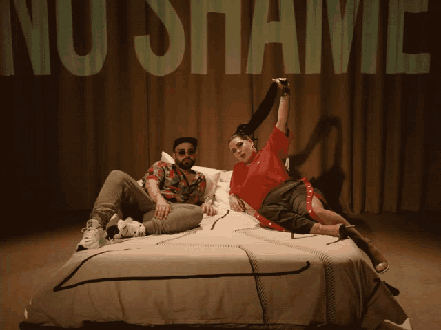 a man and a woman are laying on a bed in front of a curtain that says " nu shaivi "