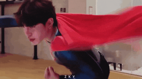 a man wearing a red cape and a superhero costume with the letters zky on the bottom