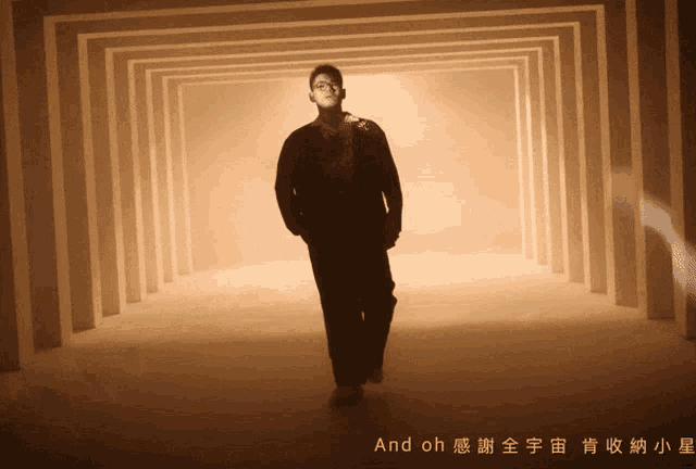 a man in a black jacket is walking through a tunnel with chinese writing