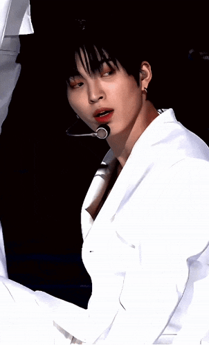 a close up of a man wearing a microphone and a white shirt