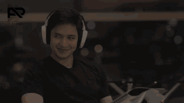 a man wearing headphones is smiling and holding a book with the year 2022 on the bottom