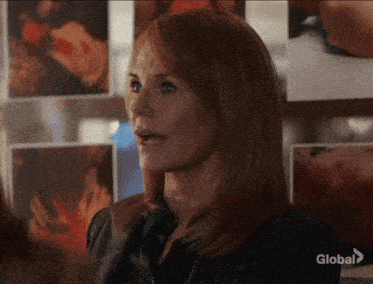 a woman in a black shirt is standing in front of a wall with pictures on it that says global