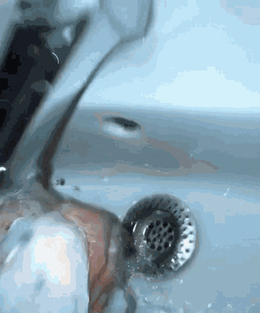 a person is washing their hands in a sink with water coming out of the drain