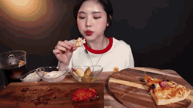 a woman is eating a slice of pizza on a wooden cutting board .
