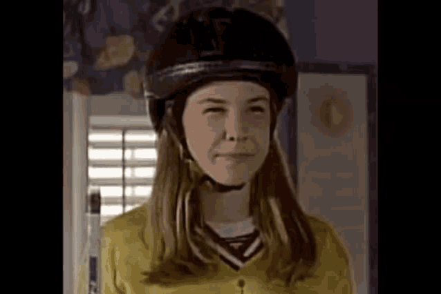 a young girl wearing a helmet is smiling in a room .