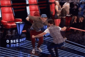 two men are dancing on a stage with a sign that says o ses on it