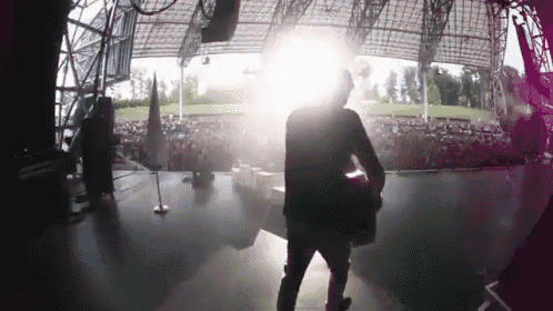 a man is walking on a stage with a light shining on him
