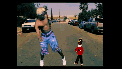 a man without a shirt is standing on a street next to a sock monkey