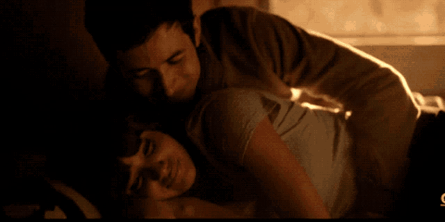 a man and a woman are hugging in a dark room with the letters c on the bottom