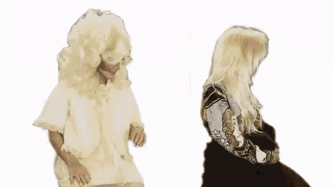 a woman in a wig is standing next to another woman in a fur coat on a white background .