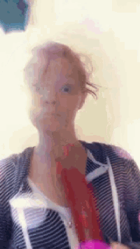 a woman is making a funny face while holding a pink brush