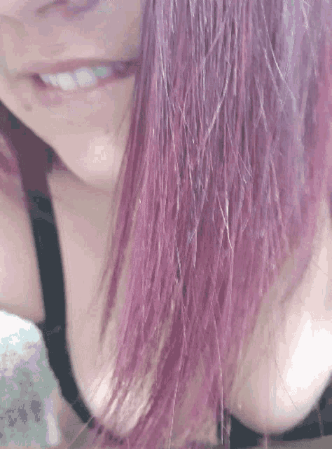 a woman with purple hair is smiling and wearing a bra