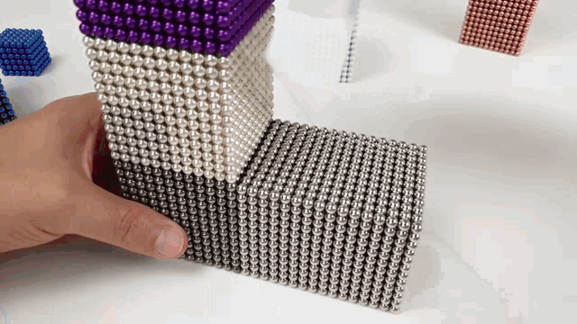 a person is holding a stack of magnet beads in their hand