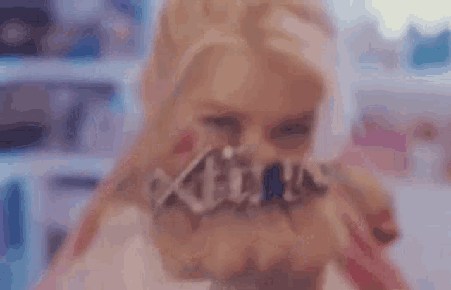 a close up of a woman holding a necklace that says ' x ' on it