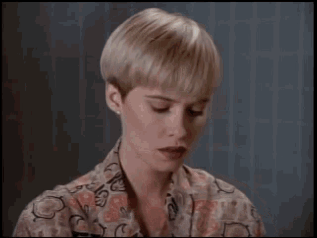 a woman with short blonde hair holds a piece of paper