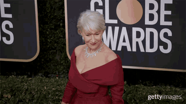 a woman stands in front of a sign that says globe awards