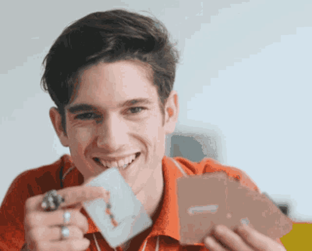 a man with a ring on his finger is smiling while holding a card that says ' a ' on it