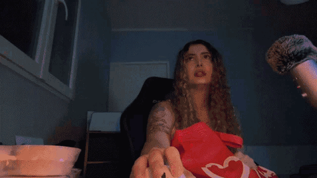 a woman in a red apron with a heart on it is sitting in a chair