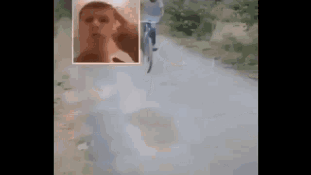 a man is riding a bicycle down a road while smoke is coming out of his mouth .