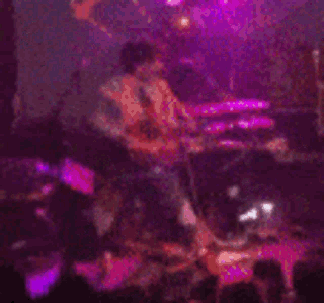 a blurry picture of a band on stage with purple lights behind them